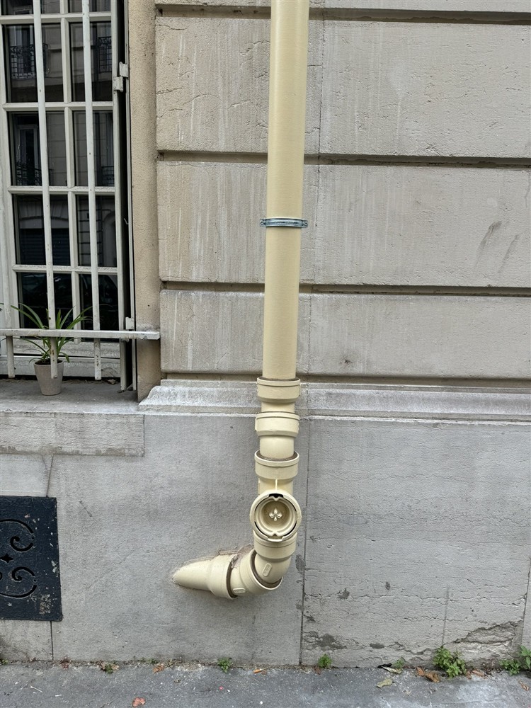 Pied de descente beige avec tampon de visite en façade.
